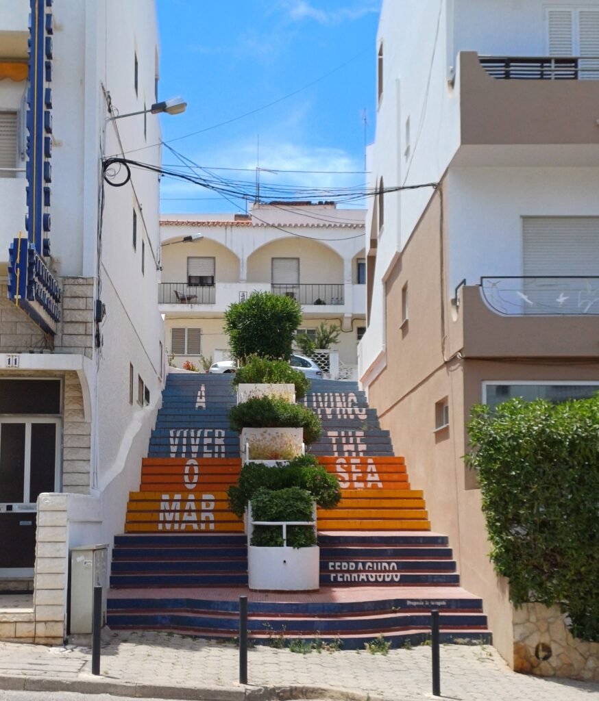 Colorful staircase in Ferragudo with artistic text and decorations on the steps.