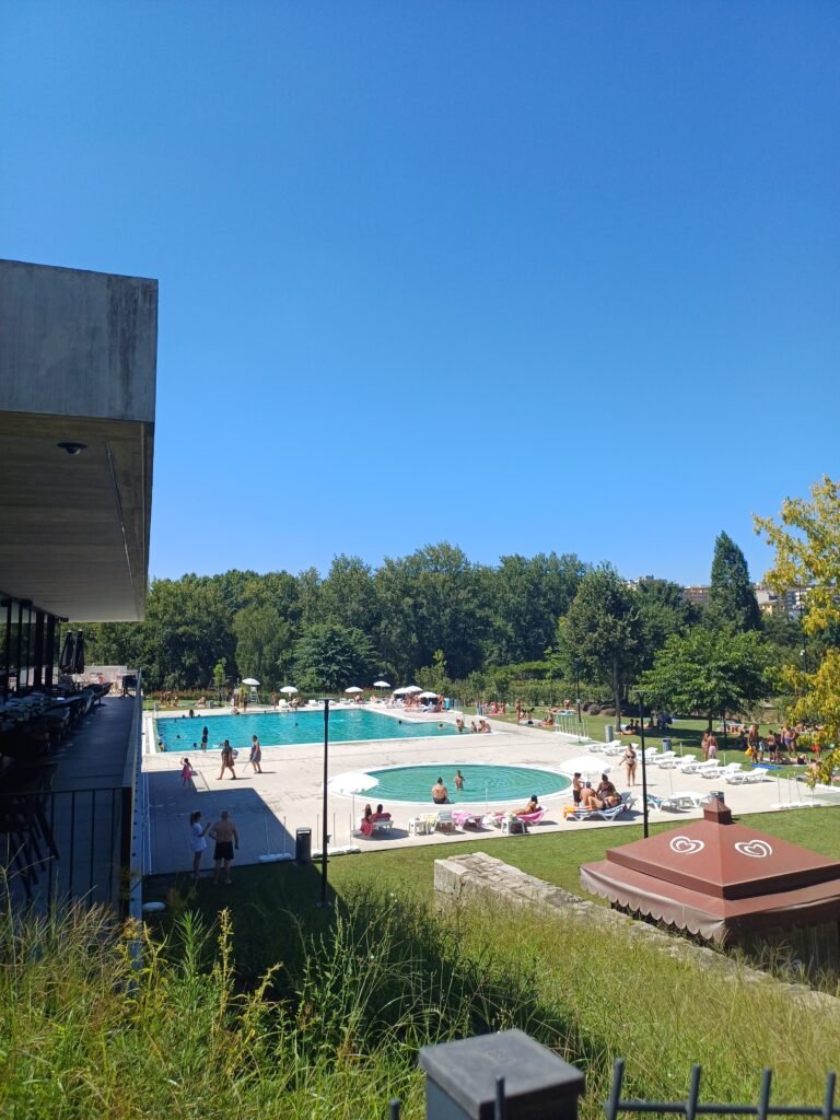 A wide view of Piscina Verde in Paredes, showcasing the spacious layout with large and small pools surrounded by greenery.