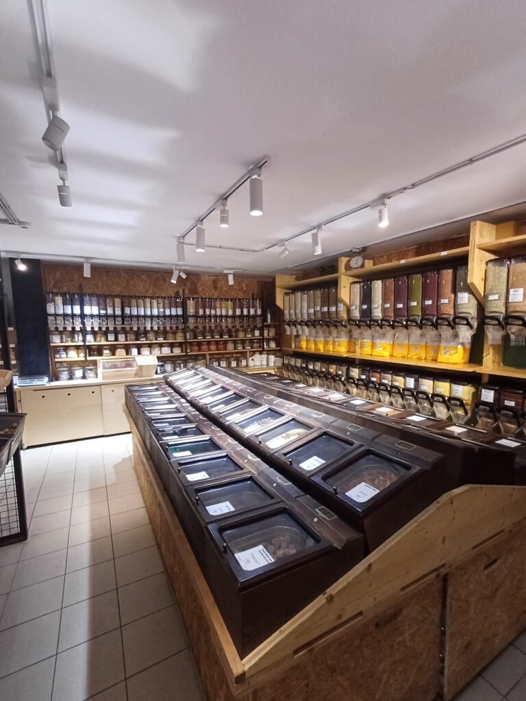 Bulk shopping area at Maçaroca, filled with containers of organic nuts, grains, dried fruits, among other products, promoting sustainable shopping in Porto