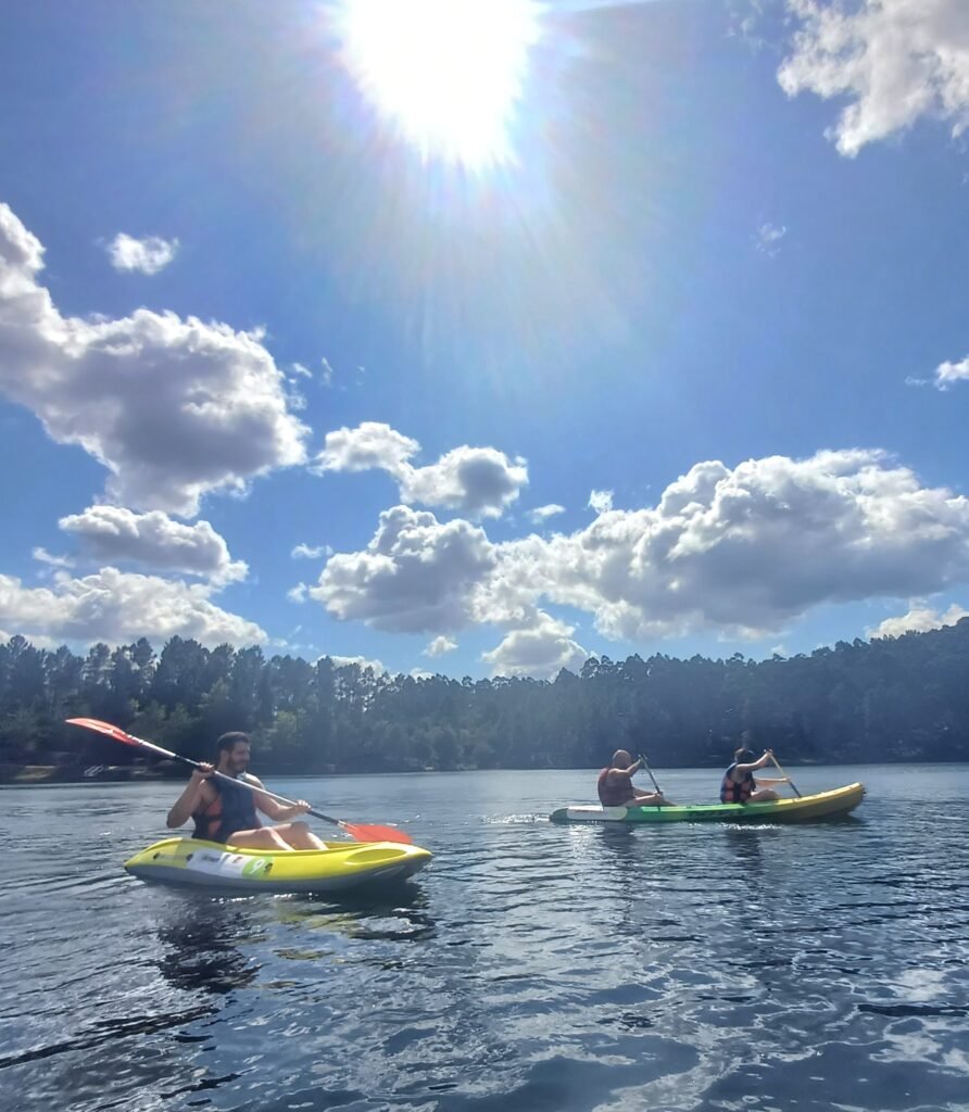 Friends paddling a kayak on the calm waters of Barragem da Queimadela