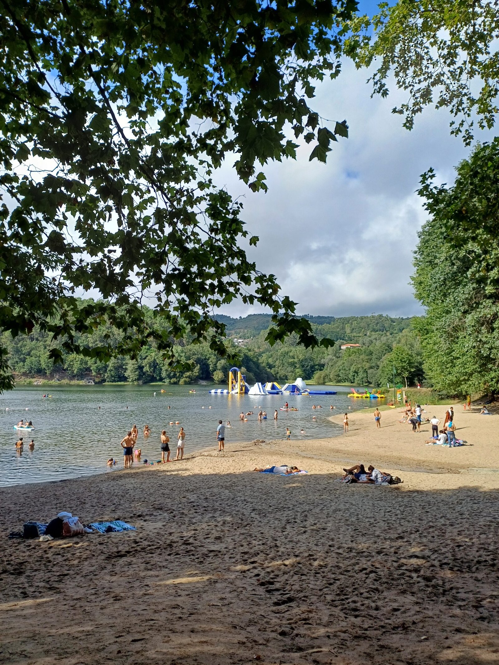 View of Praia Fluvial at Barragem da Queimadela, featuring a sandy beach area by the reservoir with clear water.